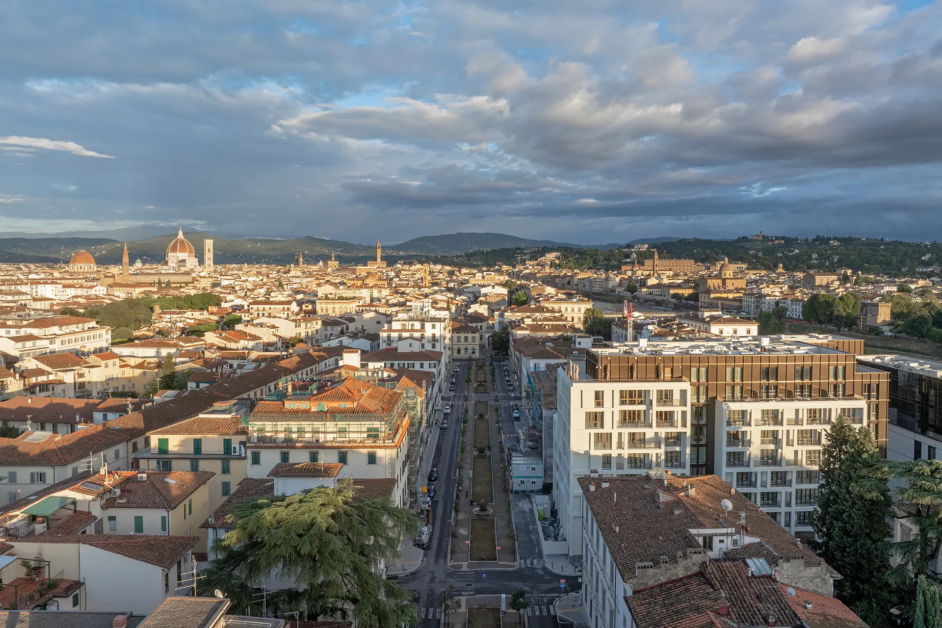 Vista panoramica di Firenze al tramonto con il Duomo, edifici storici e colline sullo sfondo.